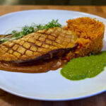 Pan-roasted duck breast with crispy skin, mole poblano, Mexican red rice, and bright green cilantro-lime sauce, inspired by Jake Kelley's Holy Mole dish on MasterChef Season 16.